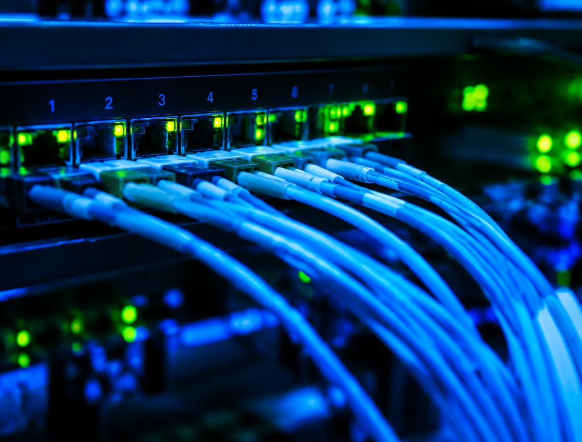Network switch with rows of connected fiber optic cables and glowing green port lights